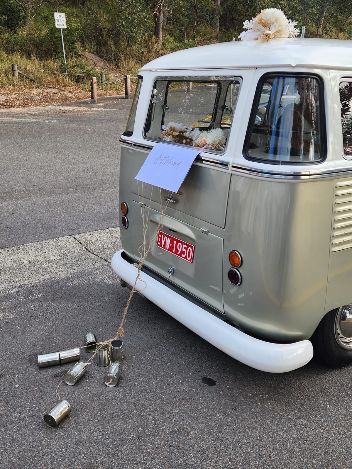 Just married vintage Kombi with tin cans and florals